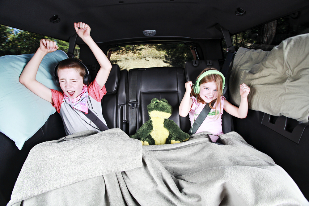 Crianças cantando no banco de trás de um carro.